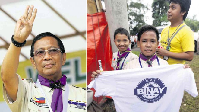 POLITICAL ‘HUNGER GAMES’  Vice President Jejomar Binay flashes the Boy Scout salute at the opening ceremony of the Philippine Scouting Centennial Jamboree for Luzon at the Boys Town Complex in Marikina City. At right, a Boy Scout shows a T-shirt bearing the face of Binay, president of the Boy Scouts of the Philippines for 20 years now.  LYN RILLON