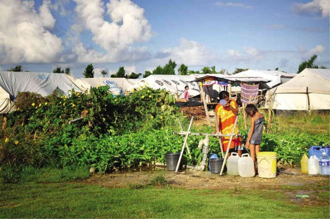 RESIDENTS fetch water from the communal water source at the “tent city,” a relocation site for seaside families displaced by Supertyphoon “Yolanda” that ravaged Eastern Visayas one year ago. MELVIN GASCON/INQUIRER NORTHERN LUZON 