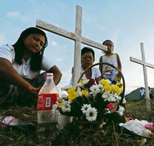 LOST KIN Merlita Cawaja, Mirasol Dagabi and Ira Nicole Cawaja visit their loved ones who died during the typhoon at a mass grave at Holy Cross Memorial Garden in Barangay Basper, Tacloban City. RAFFY LERMA