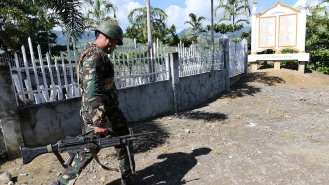 A soldier secures the site where members of a Muslim political clan in Salman, Ampatuan town, in Maguindanao murdered on Nov. 23, 2009, 58 people, 32 of them journalists. Five years after the massacre, the Ampatuan clan remains influential in Maguindanao province, holding sway even in the villages five years after its patriarch and his sons were arrested and charged with murder.  PHOTO BY JEOFFREY MAITEM/ MINDANAO BUREAU
