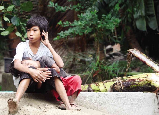 CHILDREN take comfort in each other after the abandoned truck they had been living in was washed away by floodwaters in Boljoon town, southern Cebu province, at the height of Tropical Storm “Queenie.” TONEE DESPOJO/CEBU DAILY NEWS 