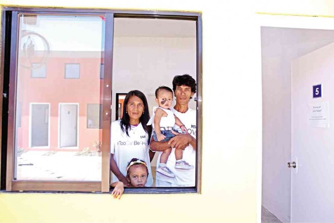 A COUPLE and their children who survived the onslaught of Supertyphoon “Yolanda” look out the window of their new house built by SM Cares, a program to rebuild the areas devastated by Yolanda and spearheaded by the country’s biggest mall developer. LITO TECSON/CEBU DAILY NEWS 
