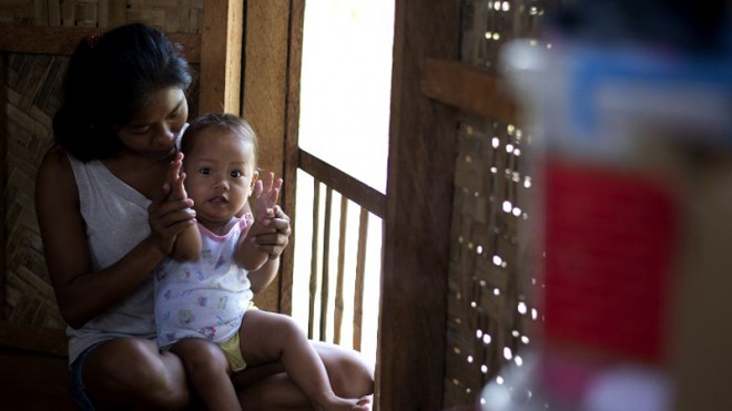 In this picture taken on Oct. 17, 2014, Emily Sagalis holds her baby girl inside her house in Tacloban, Leyte. Emily Sagalis gave birth on a concrete slab after battling storm surges that killed thousands, then like many new mothers in razed communities of the Philippines began another perilous struggle for survival with her baby. AFP PHOTO/NOEL CELIS