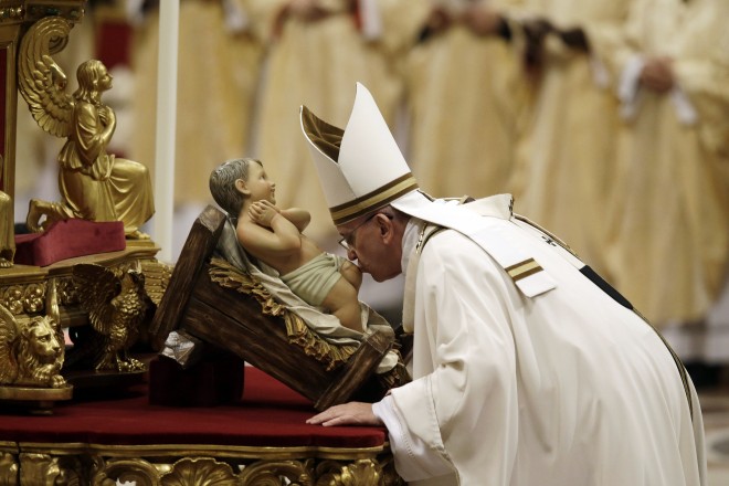 Pope Francis kisses a statue of Baby Jesus as he celebrates the Christmas Eve Mass in St. Peter's Basilica at the Vatican, Wednesday, Dec. 24, 2014. (AP Photo/Gregorio Borgia)