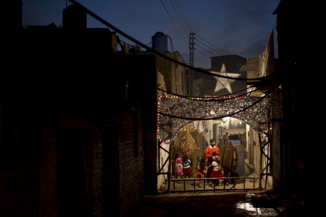 Pakistani Christians gather in an alley of a Christian neighborhood decorated with festive lights for Christmas in Islamabad, Pakistan, Wednesday, Dec. 24, 2014. (AP Photo/Muhammed Muheisen)