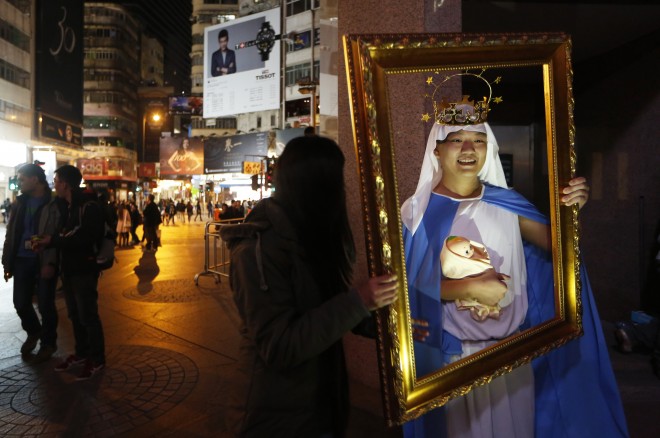 A man dressed as the Virgin Mary with baby Jesus poses for photographs during the early hours of Christmas Day celebrations in the Causeway Bay shopping district in Hong Kong Thursday, Dec. 25, 2014.  (AP Photo/Kin Cheung)