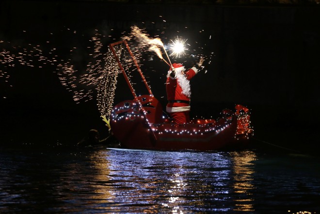 A man dressed as Santa Claus lights flares as he stands on a boat in Imperia, near Genoa, Italy, Wednesday, Dec. 24, 2014. AP