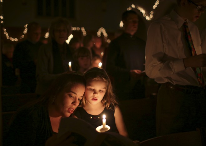 Rachel Boelke sings "Silent Night" with her daughter, Lilja, 7, and the rest of the congregation at the end of the Intergenerational Christmas Eve Service at Pilgrim Lutheran Church in St. Paul, Minn., Wednesday, Dec. 24, 2014. AP