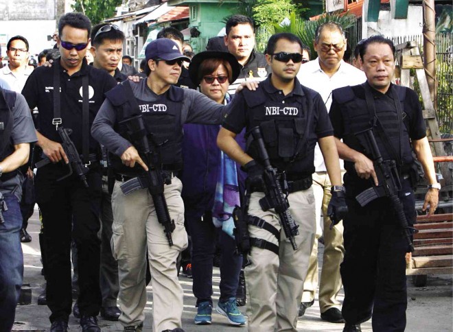 MAN-TO-MAN GUARDING    NBI agents provide a human shield for Justice Secretary Leila de Lima (center), as she leads the second inspection of New Bilibid Prison on Thursday.  The Justice chief ordered the demolition of the luxurious quarters of drug lords and gang members at the maximum security compound after an initial inspection on Monday uncovered drugs, sex toys and assorted contraband in cells renovated into luxe quarters. RAFFY LERMA 