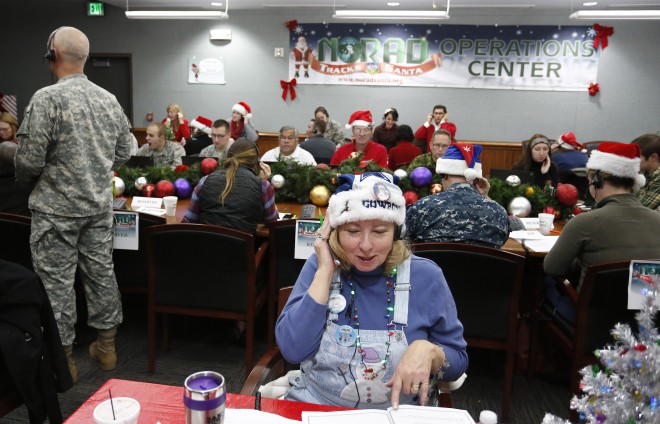 Volunteer Patty Shook takes a phone call from a child asking where Santa is and when he will deliver presents to her home, inside a phone-in center during the annual NORAD Tracks Santa Operation, at the North American Aerospace Defense Command, at Peterson Air Force Base, Colo., on Wednesday, Dec. 24, 2014. Patty and her husband, Bryan, who is retired from the Air Force, have been volunteering at NORAD each Christmas Eve for five years, fielding calls from children from all over the world eager to hear about Santa's progress. (AP Photo/Brennan Linsley)