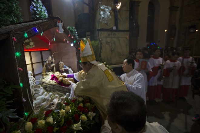 Chinese bishop Joseph Li Shan places a statue of baby Jesus in a replica of a stable as he takes part in a mass on the eve of Christmas at the South Cathedral official Catholic church in Beijing, China, Wednesday, Dec. 24, 2014. (AP Photo/Ng Han Guan)