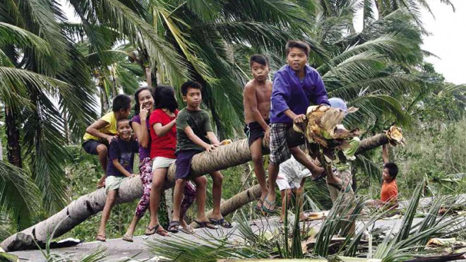 HORSING AROUND AFTER STORM  Children play and sit on fallen coconut trees along the highway in Sulat town, Eastern Samar province, in the aftermath of  Tropical Storm “Ruby.”  RAFFY LERMA