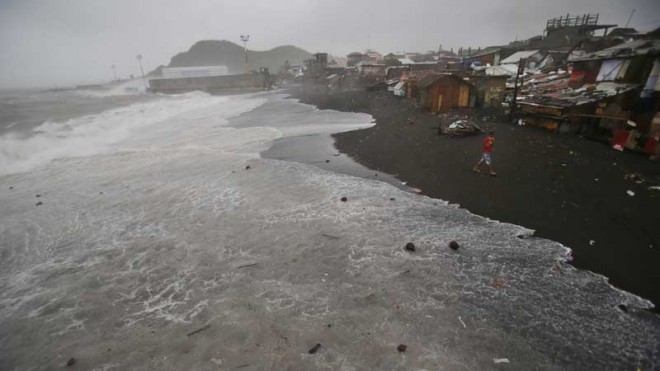 Strong waves caused by Typhoon Hagupit approach a coastal village in Legazpi, Albay province, eastern Philippines on Sunday, Dec. 7, 2014. Typhoon Hagupit knocked out power, mowed down trees and sent more than 800,000 people into shelters before it weakened Sunday, sparing the central Philippines the type of devastation that a monster storm brought to the region last year. (AP Photo/Aaron Favila)