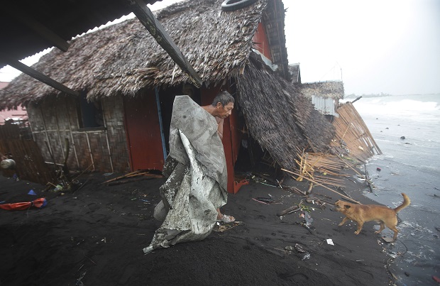 A Filipino man carries a dirty plastic sheet from his house after strong waves from Typhoon Ruby battered a coastal village in Legazpi, Albay province, eastern Philippines on Monday, Dec. 8, 2014.  AP