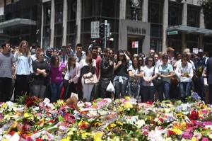 Staff members from the Lindt Chocolat Cafe with their arms linked pay tribute to their colleague who lost his live during a siege at the popular coffee shop at Martin Place in the central business district of Sydney, Australia, Tuesday, Dec. 16, 2014. AP