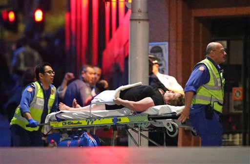 An injured hostage is wheeled to an ambulance after shots were fired during a cafe siege at Martin Place in the central business district of Sydney, Australia, Tuesday, Dec. 16, 2014.  AP PHOTO/ROB GRIFFITH 