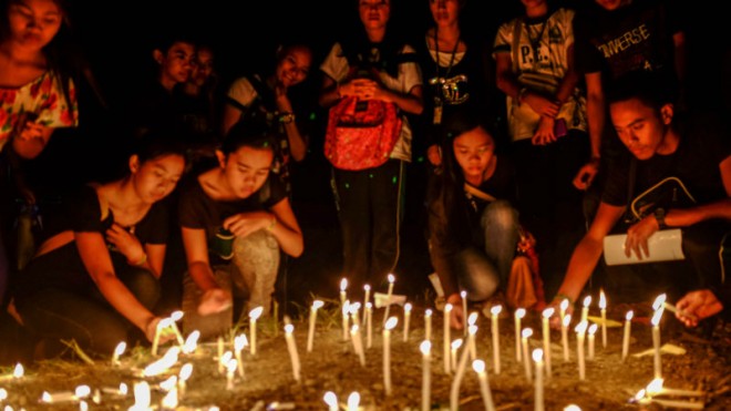 Students from Central Mindanao University  light up candles at the main gate of CMU a day after the deadly bus bombing that killed 11 people and injured 41 others. Authorities said extortion is being eyed as motive in the attack.  PHOTO BY BOBBLY LAGSA 