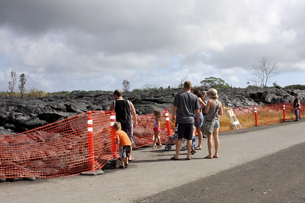 Visitors view a section of cooled lava from lava flow that began on June 27 as it approaches a shopping center in Pahoa, Hawaii, Friday, Dec. 19, 2014. Lava flowing in a rural Hawaii town continues to slow down and is estimated to reach a shopping center in about eight days. AP
