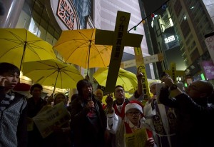 Pro-democracy protesters hold yellow umbrellas and paper crosses during in the early hours of Christmas Day in the Causeway Bay shopping district in Hong Kong Thursday, Dec. 25, 2014 as they demand genuine universal suffrage. AP