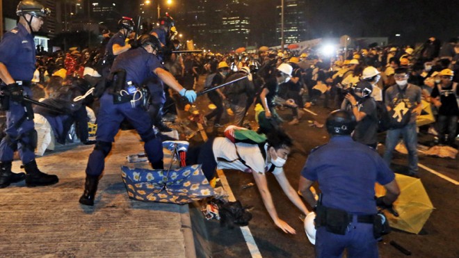 Police officers throw a pro-democracy protester on the main road outside government headquarters in Hong Kong Sunday, Nov. 30, 2014. Hundreds of pro-democracy protesters faced off with Hong Kong police late Sunday, stepping up their movement for genuine democratic reforms after being camped out on the city's streets for more than two months. (AP Photo/Kin Cheung)