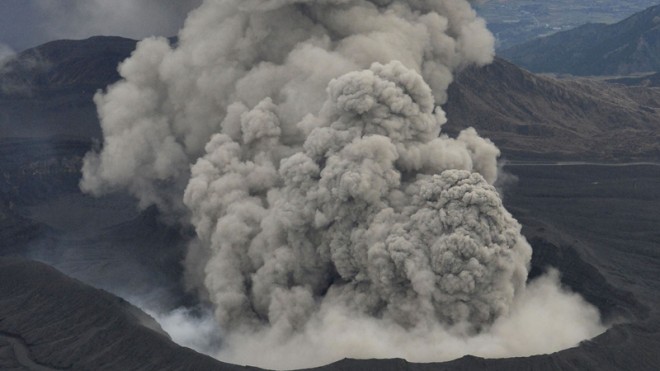 In this Nov. 26, 2014 photo, volcanic smoke billows from Mount Aso, Kumamoto prefecture, on the southern Japanese main island of Kyushu. The volcano is blasting out chunks of magma in the first such eruption in 22 years, causing flight cancellations and prompting warnings to stay away from its crater. The Japan Meteorological Agency said Friday, Nov. 28 that Mount Aso had spewed out lava debris and smoke, shooting plumes of ash a kilometer (3,280 feet) into the sky. The observatory does not expect the eruption to increase in scale. (AP Photo/Kyodo News)