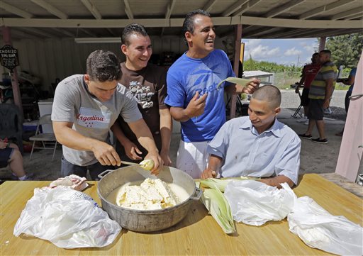 In this photo taken Sept. 28, 2014, from left, Jose Fuente Lastre, prepares a tamal as Maikel Villavicencio, Wilfredo Suarez, and Yanier Martinez Diaz, have fun during a gathering of rafters who came together risking their lives in the 110-mile journey at sea, in Miami. AP 