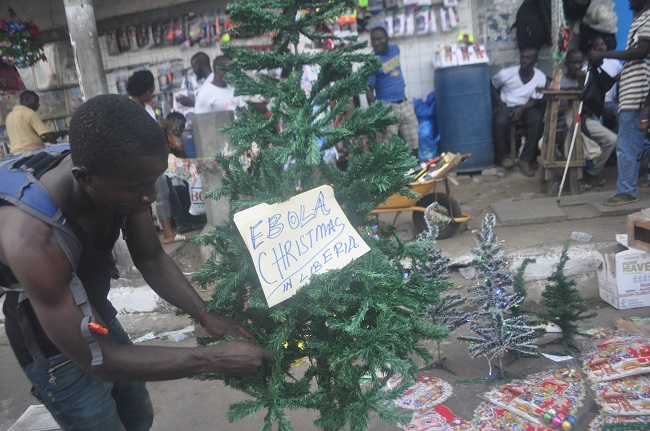 A Liberian man arranges a Christmas tree at a shop in Monrovia, Liberia, Wednesday, Dec. 24, 2014. The deadly Ebola epidemic in Sierra Leone means no festive parties at the beach, no carolers singing at night. Authorities this year have banned any activities that could further the spread of the highly contagious virus now blamed for killing more than 7,000 people in West Africa over the past year. AP