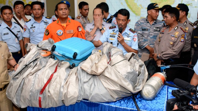 Commander of Indonesian Air Force 1st Operational Command Rear Marshall Dwi Putranto, center, shows the airplane parts and a suitcase found floating on the water near the site where AirAsia Flight 8501 disappeared, during a press conference at the airbase in Pangkalan Bun, Central Borneo, Indonesia, Tuesday, Dec. 30, 2014. Bodies and debris seen floating in Indonesian waters Tuesday, painfully ended the mystery of AirAsia Flight 8501, which crashed into the Java Sea and was lost to searchers for more than two days.  AP PHOTO/DEWI NURCAHYANI
