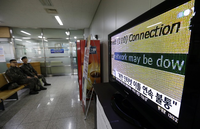 South Korean army soldiers watch a TV news program reporting North Korean websites suffer shutdown, at the Inter-Korean Transit Office near the border village of Panmunjom in Paju, South Korea, Wednesday, Dec. 24, 2014. Key North Korean websites suffered intermittent outages Tuesday after a nearly 10-hour shutdown that followed a U.S. vow to respond to a crippling cyberattack on Sony Pictures that Washington blames on Pyongyang. The letters read " North Korean internet suffers shutdown." AP