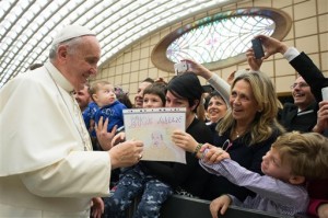 In this picture made available by the Vatican newspaper L' Osservatore Romano, Pope Francis is presented by a child with a drawing depicting a Pope's portrait and a writing which reads Merry Christmas, during an audience with the Holy See's employees in the Paul VI hall at the Vatican, Monday, Dec. 22, 2014. AP