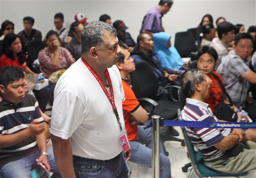 AirAsia Group CEO Tony Fernandes, center, walks past the relatives of the passengers of AirAsia flight QZ8015 at Juanda International Airport in Surabaya, East Java, Indonesia, Sunday, Dec. 28, 2014. A massive sea search was underway for the AirAsia plane that disappeared Sunday while flying from Indonesia to Singapore through airspace possibly thick with dense storm clouds, strong winds and lightning, officials said. (AP Photo/Trisnadi)