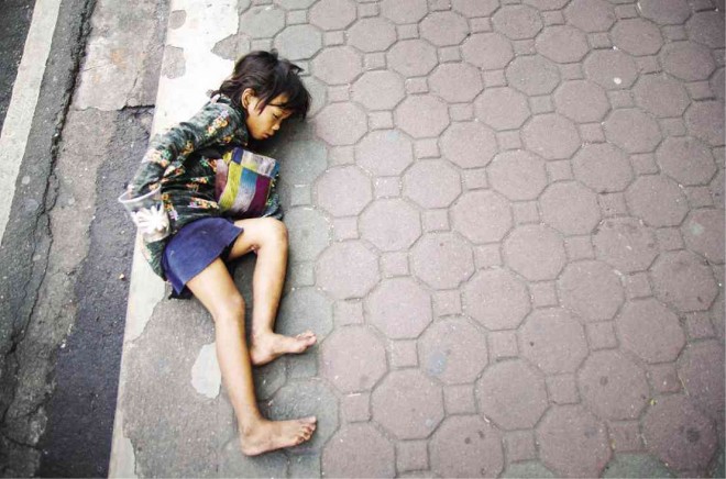 A Badjao girl sleeps on the sidewalk of Session Road in Baguio City, while her mother (not seen in the photo) watches from the opposite of the street. Richard Balonglong/Inquirer Northern Luzon