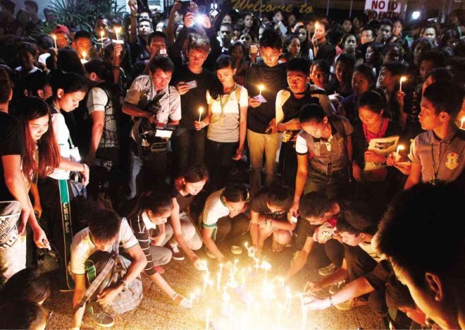 STUDENTS, teachers and employees of  Central Mindanao University in Barangay Dologon, Maramag town, Bukidnon province, light candles and  pray for the victims of the Dec. 9  bus bombing near the university. Five of the 11 fatalities and 11 of the more than 40 wounded were students of the university. JB R. DEVEZA/INQUIRER MINDANAO