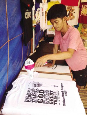 SHIRT designer Jonathan Culubio dries the print on a Pope Francis shirt in his studio in Cebu City. CARINE ASUTILLA/INQUIRER VISAYAS 