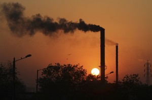 Birds fly past at sun set as smoke emits from a chimney at a factory in Ahmadabad, India, Monday, Dec. 8, 2014. AP FILE PHOTO