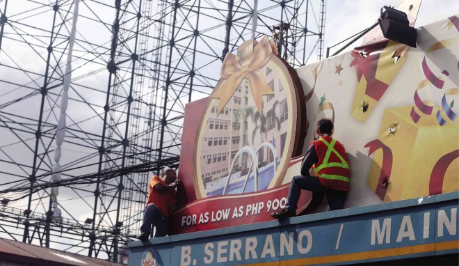 IN PREPARATION for Typhoon “Ruby,” MMDA crews remove tarpaulin billboards on Edsa, including one for the January 2015 visit of Pope Francis (left), as a safety precaution. 