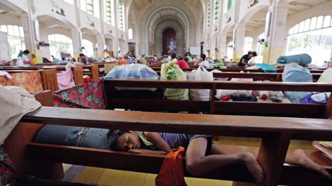 REFUGE IN THE HOUSE OF GOD   A child uses  a pew  as a makeshift bed inside the  Redemptorist Church in Tacloban City where residents evacuated  ahead of the landfall of Typhoon “Ruby” (international name: Hagupit)  in the Visayas. The typhoon threatens to whip up storm surges in the disaster-weary central Philippines that, a year ago, was flattened by Supertyphoon “Yolanda.” RAFFY LERMA