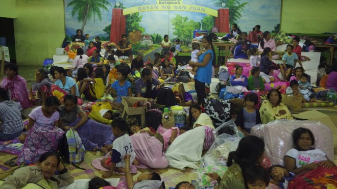 Residents stay at an evacuation center as Typhoon Hagupit hits San Juan town, Batangas province, eastern Philippines on Monday, Dec. 8, 2014. Typhoon Hagupit weakened into a storm Monday after it left at least three people dead and sent more than a million others into shelters, sparing the central Philippines the massive devastation that a monster storm inflicted on the region last year. (AP Photo/Aaron Favila)