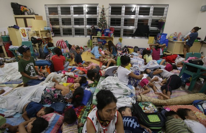 Filipino families seek refuge at a school used as an evacuation center as they prepare for Typhoon Hagupit in Legazpi, Albay province, eastern Philippines Saturday, Dec. 6, 2014. Typhoon Hagupit slammed into the central Philippines' east coast late Saturday, knocking out power and toppling trees in a region where 650,000 people have fled to safety, still haunted by the massive death and destruction wrought by a monster storm last year. (AP Photo/Aaron Favila)