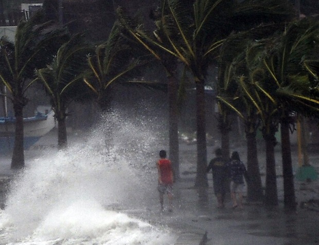 Residents walk past high waves brought about by strong winds as it pound the seawall, hours before Typhoon Hagupit passes near the city of Legazpi on December 7, 2014.  Typhoon Hagupit tore apart homes and sent waves crashing through coastal communities across the eastern Philippines, creating more misery for millions following a barrage of deadly disasters.      AFP PHOTO/TED ALJIBE