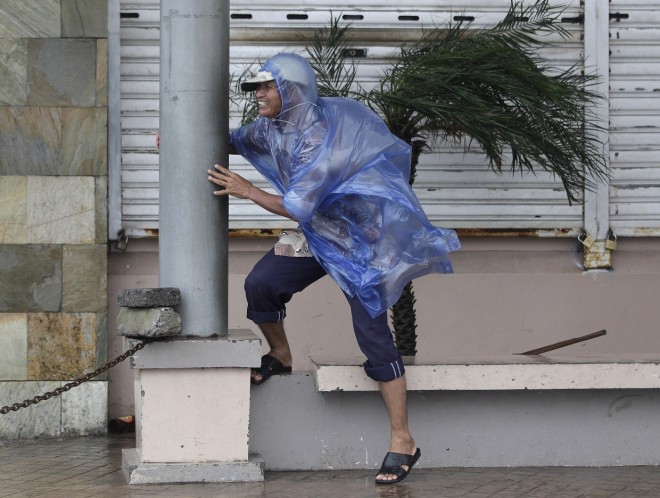 A man holds on to a pole as strong winds blow brought by Typhoon Hagupit in Legazpi, Albay province, eastern Philippines on Sunday, Dec. 7, 2014. Typhoon Hagupit slammed into the central Philippines' east coast late Saturday, knocking out power and toppling trees in a region where 650,000 people have fled to safety, still haunted by the massive death and destruction wrought by a monster storm last year. (AP Photo/Aaron Favila)