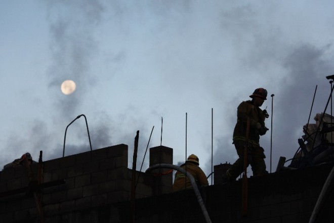 The moon is seen over firefighters battling a fire that destroyed a seven-story apartment building under construction on Dec. 8, 2014, in Los Angeles, California. The fire also damaged nearby high-rise buildings and shut down freeways, causing massive traffic problems for morning commuters.  DAVID MCNEW/GETTY IMAGES/AFP