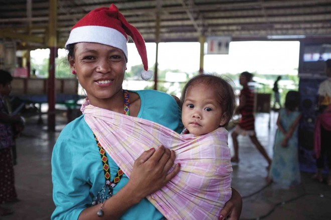 Carrying her 1-year-old baby, Christine, in a piece of cloth wrapped around her body called “salulo,” Ata-Manobo mother Mercy Licunan roams Davao City to ask for Christmas gifts.  INQUIRER MINDANAO 