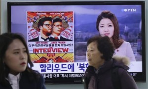 In this Monday, Dec. 22, 2014, file photo, people walk past a TV screen showing a poster of Sony Picture's "The Interview" in a news report, at the Seoul Railway Station in Seoul, South Korea. A South Korean activist said Wednesday, Dec. 31, 2014, that he will launch balloons carrying DVDs of Sony’s “The Interview” toward North Korea. AP