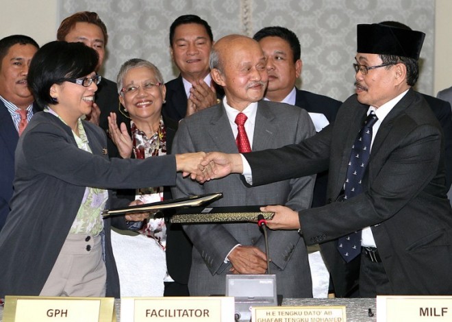 Miriam Coronel Ferrer (L), chairperson of the government negotiating panel for peace talks with the Moro Islamic Liberation Front (MILF), exchanges documents with MILF Chief Negotiator Mohagher Iqbal (R) during a press conference at a hotel in Kuala Lumpur on January 25, 2014. AFP FILE PHOTO