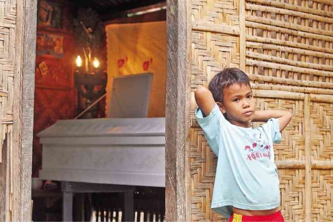 THE GRIEF may be too deep but it doesn’t show on the face of 8-year-old Jason Baldado, who lost his mother Alona to flood spawned by Tropical Storm “Queenie” in Malabuyoc town, Cebu province. The coffin bearing Alona’s body lies inside the Baldado home. TONEE DESPOJO/CEBU DAILY NEWS