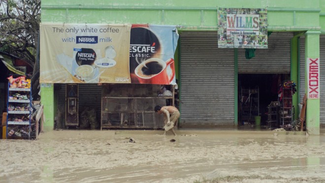 A resident clears the mud off outside his business establishment at Alcantara town, Cebu province, on Tuesday, Dec. 30, 2014. Flash floods and landslides triggered by Tropical Storm Jangmi left 31 people dead in the Philippines, including in areas still recovering from last year's Typhoon “Yolanda” (Haiyan), officials said Tuesday.  AP PHOTO/FRUHLEIN ECONAR