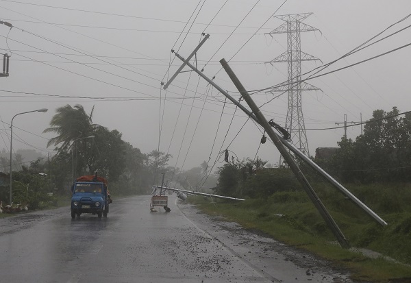Motorists pass by toppled electrical posts due to strong winds brought by Typhoon Hagupit in Camalig, Albay province, eastern Philippines on Sunday, Dec. 7, 2014. AP