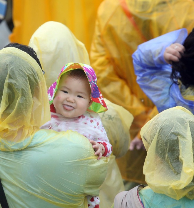 A baby manage to smile while the parents listen to the mass of Pope Francis in Tacloban airport despite the rain brought by typhoon amang. CDN