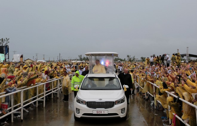 Pope Francis, wearing raincoat, blesses the crowd after the mass near the Tacloban Airport, Saturday, January 17, 2015,  enroute to Palo, Leyte to visit families of typhoon Yolanda victims. Leyte and the nearby provinces is under typhoon signal number 2 when the Pope arrived. (Photo by Benhur Arcayan/Malacanang Photo Bureau)
